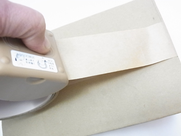 テープをカットするために親指で土台を押し込んでいる写真